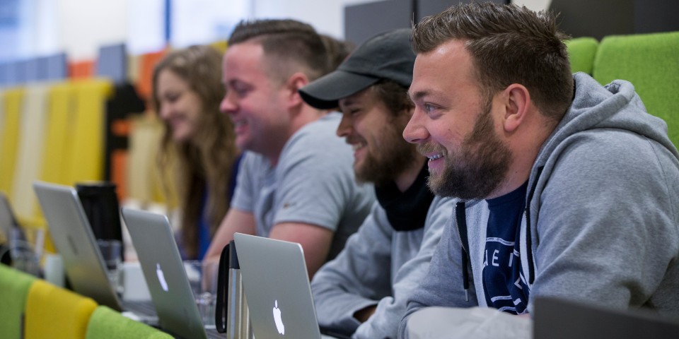 Fire gymnasieelever sidder med deres computere i et auditorium